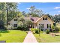 A charming two-story home features a manicured lawn with mature trees, on a sunny day at 50 Persian Pl, Whitesburg, GA 30185