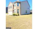 Two story tan brick and siding home with an attached two car garage and a lawn at 116 Jodi Pl, Locust Grove, GA 30248