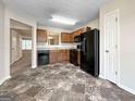 Well-lit kitchen with black appliances, wood cabinets, and tile floors, open to a view of additional living space at 5828 Union Walk Dr, Union City, GA 30291