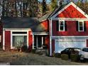 Front exterior of red two-story home with a two-car garage and mature landscaping at 7472 Woods Ct, Lithonia, GA 30058