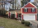 Charming red two-story home with black shutters, white garage door, and well-manicured front lawn at 7472 Woods Ct, Lithonia, GA 30058