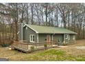 Cozy single-story home features a wooden deck, a metal roof, and lush green surroundings at 2020 Moore Rd, Moreland, GA 30259