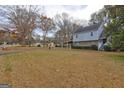 Expansive front yard with mature trees framing a two-story home with a carport and stone facade at 3954 Swathmore Ln, Duluth, GA 30096