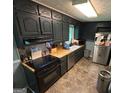 Cozy kitchen featuring dark cabinetry, stainless steel appliances, and butcher block countertops, creating a rustic charm at 2497 Old Jackson Rd, Locust Grove, GA 30248