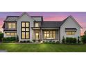 Modern farmhouse exterior at dusk, featuring a metal roof and large windows at 0 Matteo Way # 4, Fayetteville, GA 30215