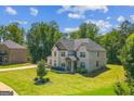 Charming two-story brick home with a lush, green lawn and mature trees providing shade and privacy at 4051 Rotterdam Pass, Hampton, GA 30228