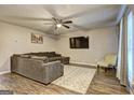 Living room with L-shaped sofa, wood-look floors, and ceiling fan at 8424 Carlington Ln, Jonesboro, GA 30236