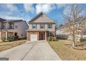 Two-story house with brick and beige siding, a two-car garage, and a landscaped front yard at 11945 Lovejoy Crossing Way, Hampton, GA 30228