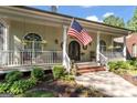 Inviting front porch features classic columns, wrought iron door and beautiful landscaping at 3806 Bill Gardner Pkwy, Locust Grove, GA 30248