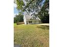 White house with gray metal roof, three-car garage, and a long driveway at 470 Harris Rockmore Loop, Covington, GA 30014