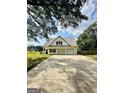 White house with gray metal roof, three-car garage, and a long driveway at 470 Harris Rockmore Loop, Covington, GA 30014