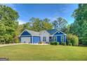 Attractive blue home with a well-manicured lawn, showcasing an attached garage and lovely landscaping at 2037 Emily Dr, Social Circle, GA 30025