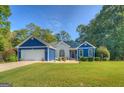 View of attractive exterior with white brick and blue accents, a lovely landscape, and large yard at 2037 Emily Dr, Social Circle, GA 30025