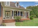 Inviting front porch with white columns, brick accents, and a decorative front door at 557 Arrowhead Cir, Rutledge, GA 30663