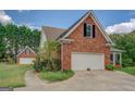 View of brick garage with white door and matching home with lush landscaping at 557 Arrowhead Cir, Rutledge, GA 30663