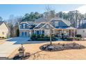 Inviting two-story home showcases a beautiful blue facade, a covered front porch, and a lovely front yard at 4960 Shade Creek Xing, Cumming, GA 30028