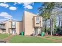 Tan two-story townhouse with green lawn and mature trees at 6036 Regent Mnr, Lithonia, GA 30058