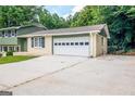 Home exterior featuring attached two-car garage, paved driveway, and manicured lawn at 6667 Ridge Moore Dr, Peachtree Corners, GA 30360