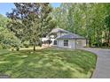 View of a two-story home with an attached garage surrounded by mature trees and lawn at 215 Kingswood Dr, Fayetteville, GA 30215