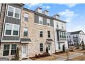 Three-story townhome with gray and white exterior, brick accents, and walkway at 295 Cobalt Dr, Fayetteville, GA 30214