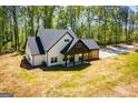 Spacious modern farmhouse with mature trees, a gravel driveway, and a dark roof at 90 Ayers Rd, Bowdon, GA 30108