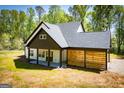 Charming home with a covered patio, open carport, wood-slat wall, and verdant lawn at 90 Ayers Rd, Bowdon, GA 30108