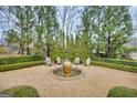 Tranquil backyard with fountain, gravel, surrounded by hedges, shrubbery and mature trees at 147 Hubbard Rd, Woodstock, GA 30188