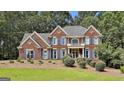 Stately brick home with blue shutters and a manicured lawn with mature landscaping and a welcoming porch at 230 Hedgewick Way, Tyrone, GA 30290