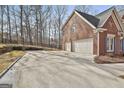 Three-car garage with a large concrete parking pad at 230 Hedgewick Way, Tyrone, GA 30290