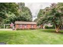 Brick home featuring a lush lawn, manicured shrubs, and a charming pergola at 3170 Ebenezer Rd, Marietta, GA 30066