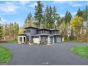 A modern home surrounded by mature trees and a driveway leading to a spacious three-car garage at 200 Simonton Rd, Lawrenceville, GA 30046