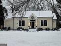 Snowy landscape showcases the charming home's inviting entrance with classic details at 213 W Hightower Trl, Social Circle, GA 30025
