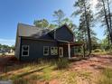 Rear exterior view featuring gray siding, a covered porch, and ample natural light at 148 Asa Moseley Rd, Mcdonough, GA 30252