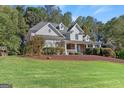 Elegant home with a sprawling lawn, covered porch, and well-manicured landscaping at 4780 Rambling Rose Dr, Cumming, GA 30040