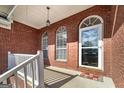 Inviting front porch with brick facade and arched windows offering a glimpse of the entry at 253 Edenwylde Ct, Hampton, GA 30228