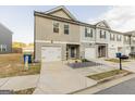 Two-story townhome with gray siding, white garage doors, and a small front yard at 4937 Lower Elm St, South Fulton, GA 30349
