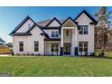 Beautiful two-story home featuring a striking white and black exterior, contrasted by a bright green lawn at 1010 Nours Cir, Lawrenceville, GA 30045