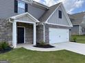 Attractive home exterior featuring a two-car garage, brick accents, and manicured lawn at 117 Oliver Dr, Locust Grove, GA 30248