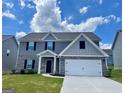 Beautiful home showcasing a two-car garage, gray siding, black shutters, and a well-maintained lawn at 117 Oliver Dr, Locust Grove, GA 30248