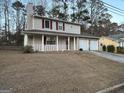 The exterior boasts a covered porch, two-car garage, and a chimney amidst mature trees at 5427 Forest Pines Dr, Lithonia, GA 30058