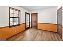 A cozy room featuring light wood laminate flooring, white and orange walls and natural light from a large window at 5427 Forest Pines Dr, Lithonia, GA 30058