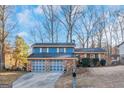 Ranch style home with brick and blue siding, two-car garage, and mature landscaping at 100 Traverse Ct, Atlanta, GA 30349