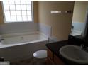 Main bathroom with a garden tub, single sink vanity, and tile flooring at 7777 Newbury Dr, Jonesboro, GA 30236