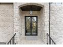 Elegant stone arched entryway with modern black framed glass double doors and lantern lighting at 220 Early Parkway Se Dr, Smyrna, GA 30082