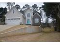 Two-story home with grey and stone facade and a bright blue front door and retaining wall at 205 Belvedere Green, Peachtree City, GA 30269
