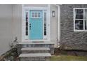 Close-up of bright blue front door, stone facade, a window, and landscaping at 205 Belvedere Green, Peachtree City, GA 30269