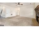 Spacious living room with a stone fireplace, a ceiling fan, neutral carpet, and access to other rooms at 1205 Heartwood Ave, Mcdonough, GA 30253