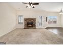 Bright living room with a stone fireplace, neutral carpet, a ceiling fan, and multiple windows at 1205 Heartwood Ave, Mcdonough, GA 30253