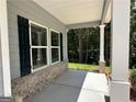 Inviting covered porch with brick base, gray siding, white trim, and classic columns adding charm at 142 Tye St, Stockbridge, GA 30281