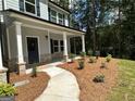 Landscaped front yard with a winding walkway leading to a cozy covered porch and painted front door at 142 Tye St, Stockbridge, GA 30281